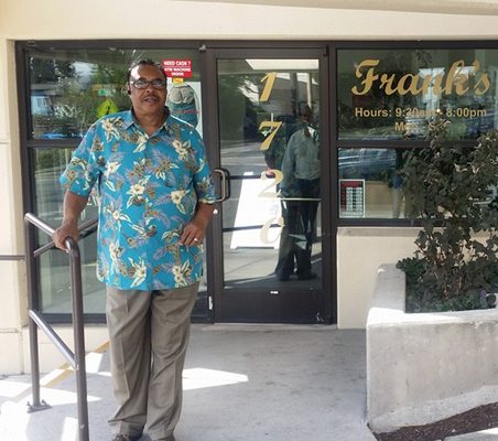 Frank, owner of Frank's Barber & Beauty Salon, standing at the shop entrance in Seattle